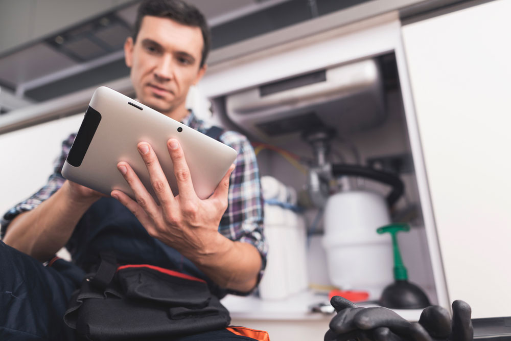 Le plombier chauffagiste intègre l'innovation dans son travail en utilisant un logiciel métier sur sa tablette pour faciliter ses interventions.