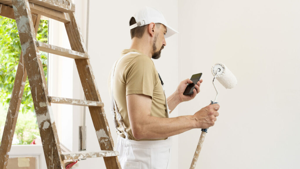 Artisan peintre envoyant un SMS à un client sur un chantier